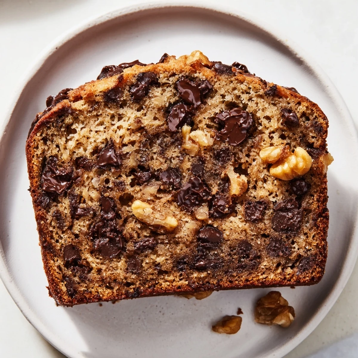 Warm slice of chocolate chip banana bread, showcasing melted chocolate and a soft, moist texture.
