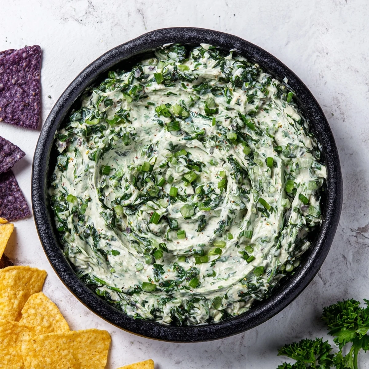 Witch's Brew Cauldron dip, creamy green and bubbling, in a dark cauldron with smoky, vibrantly colored garnishes.