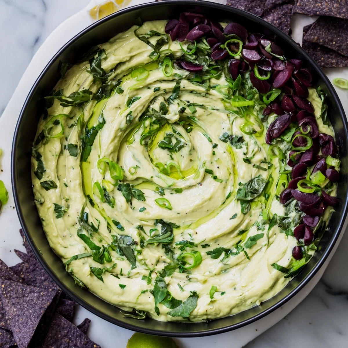 Get ready for Halloween! This Witch's Brew Cauldron displays a vibrant, creamy green dip surrounded by dark ingredients.