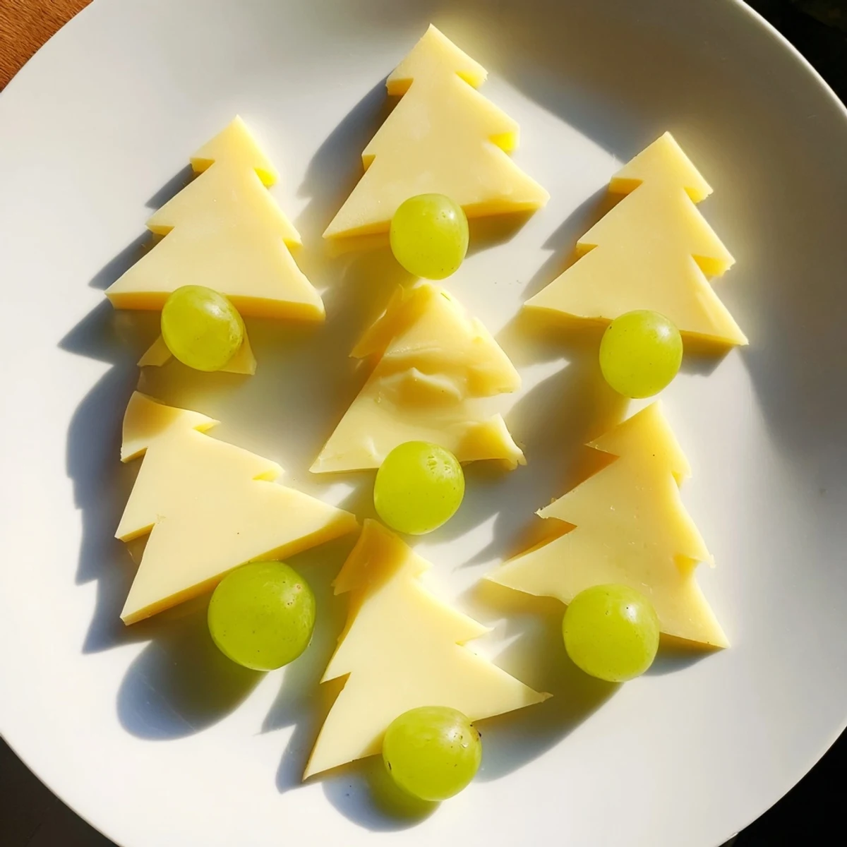 Festive Tannenbaum Border cheese board featuring triangular cheese "trees" and fresh green grapes beautifully arranged.