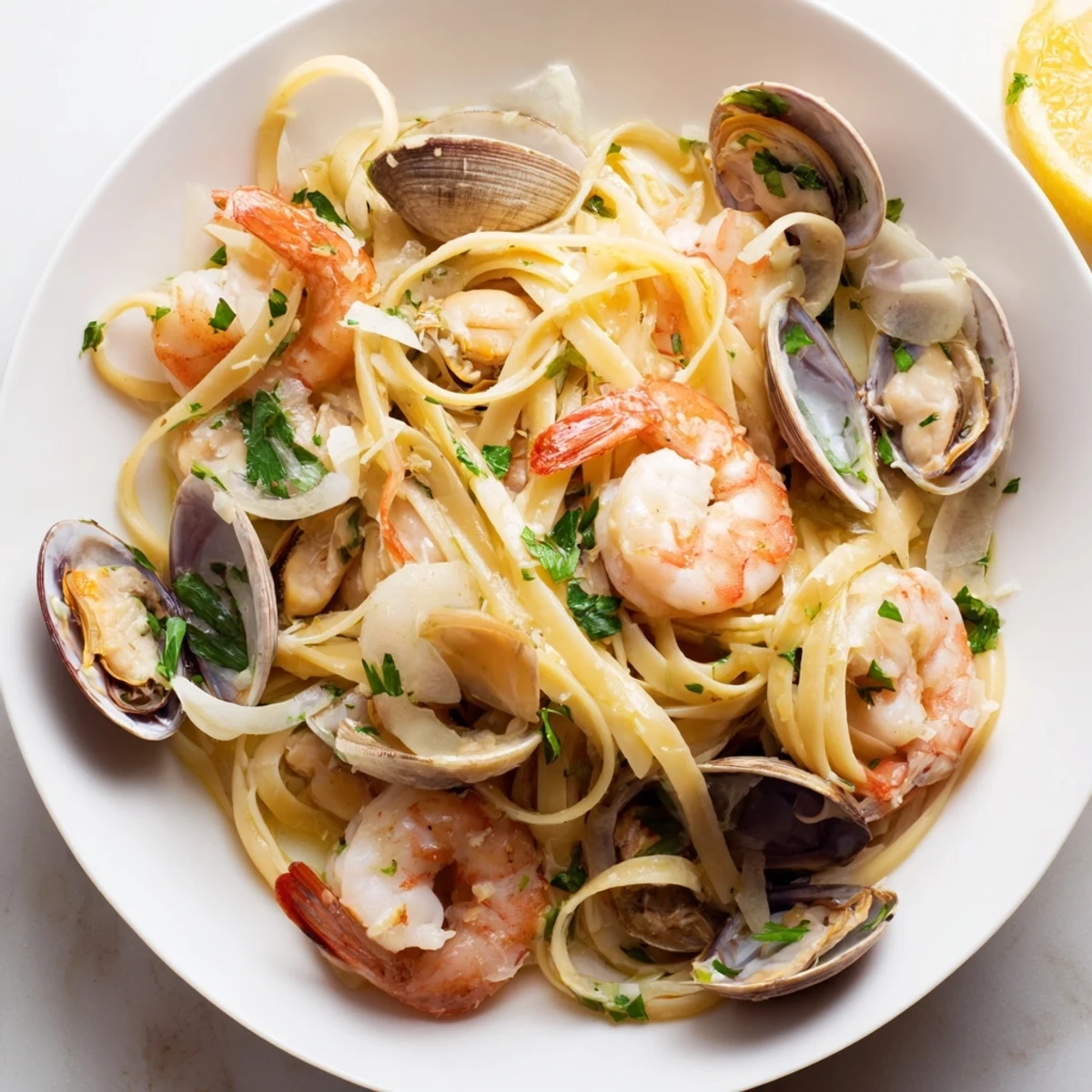 The finished Seafood Linguine steams in a white bowl, garnished with fresh parsley and lemon wedges, ready to serve immediately.  
