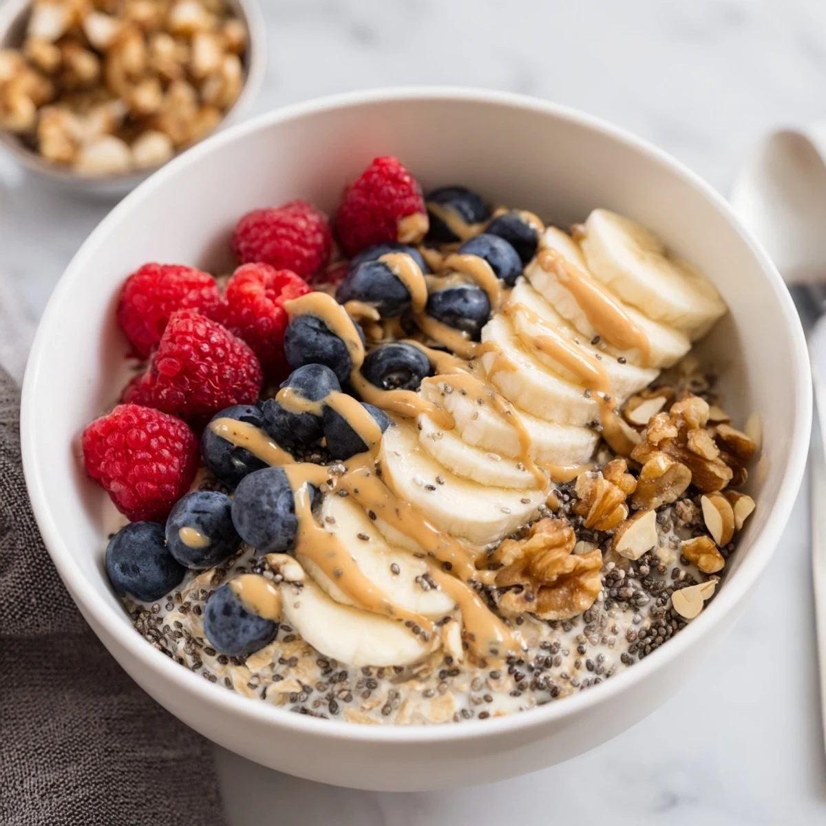 A creamy jar of Overnight Oats with chia seeds, layered with sliced banana and crunchy almonds.