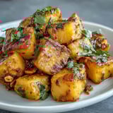 A hearty serving of curried celeriac over fluffy white rice, topped with crunchy toasted cashews and a sprinkle of herbs.