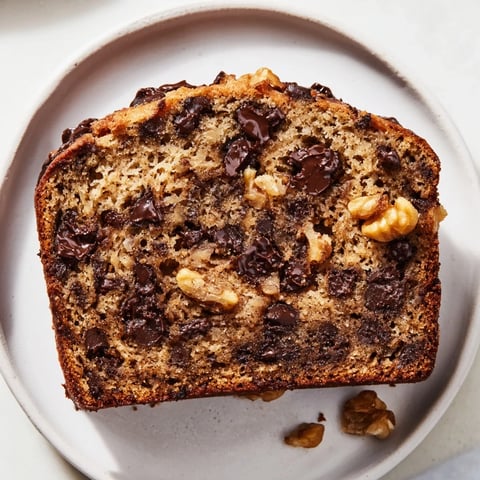 Warm slice of chocolate chip banana bread, showcasing melted chocolate and a soft, moist texture.