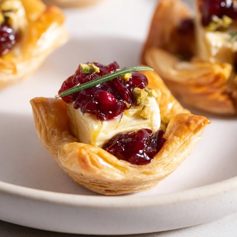 Golden-brown Mini Cranberry Brie Tart Wreath with melting brie and festive holiday garnish.