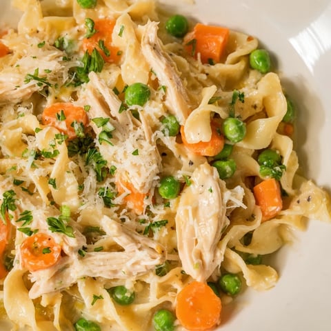 Creamy Spring Chicken Noodle Skillet with tender shredded chicken, sweet peas, and carrots.