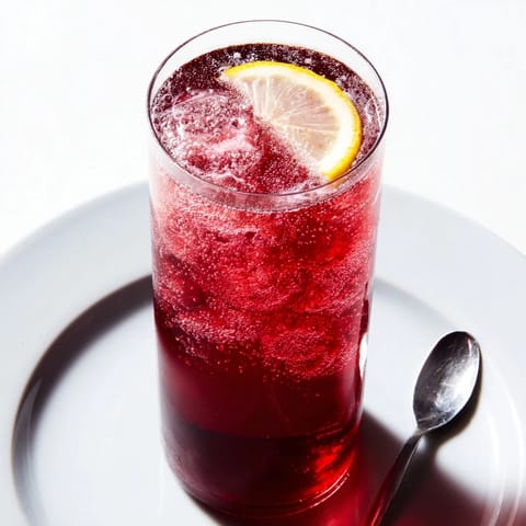 A chilled Sleepy Girl Mocktail with fizz, perfect for bedtime, shown with ice and a lemon wedge.