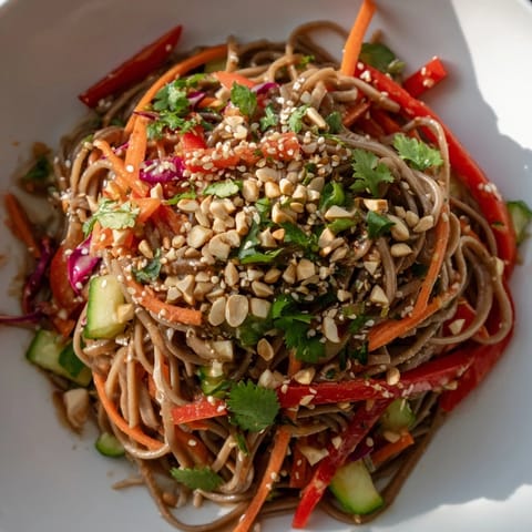 Close-up of refreshing cold noodle salad with sesame-ginger dressing, garnished with peanuts and sesame seeds.