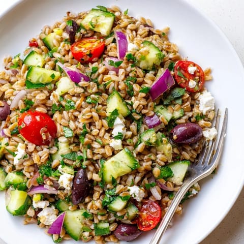 Close-up of a chilled Farro Salad Mediterranean, featuring creamy feta, briny olives, and fresh herbs over chewy grains.  