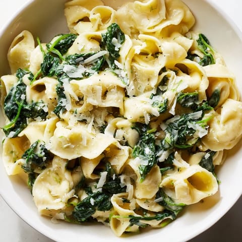 A close-up of Creamy Spinach Garlic Noodles twirled on a fork, steam rising from the garlicky cream sauce.  