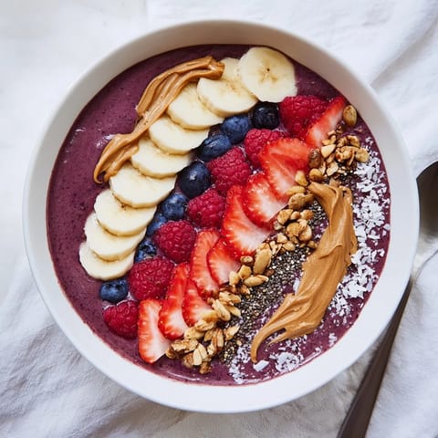 Thick frozen acai berry smoothie bowl garnished with strawberries, blueberries, chia seeds, and coconut flakes, served in a chilled bowl.