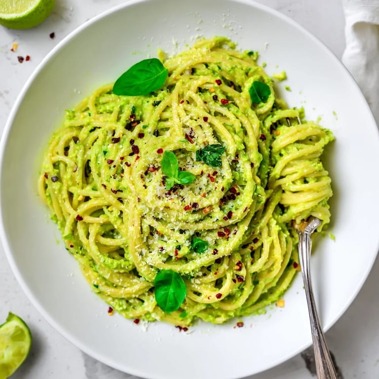 Zesty smashed avocado pasta tossed with spaghetti, topped with grated Parmesan and lime zest.