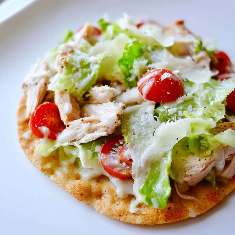 Ready-to-serve Caesar Chicken Flatbread with cherry tomatoes and extra Parmesan shavings on a rustic plate.