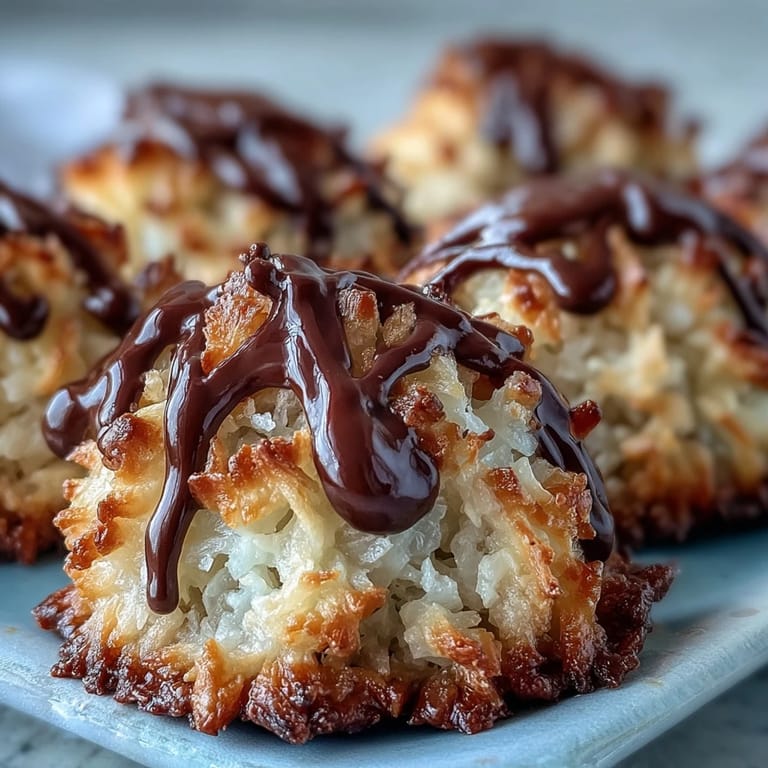 Plump, golden vegan coconut macaroons drizzled with smooth dark chocolate, a delightful dairy-free dessert option.