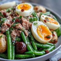 Vibrant Spring Niçoise Salad with tuna, green beans, potatoes, and soft-boiled eggs on mixed greens.